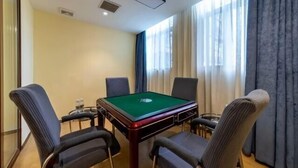 Habitación con mesa de billar, cuatro sillas, una mesita con una botella y un ventanal con cortinas.