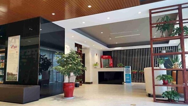 A modern lobby with a reception desk, potted plants, and a wooden ceiling. - Jinjiang Inn Select (Yangzhong Middle Yangzi Road) (Yangzhong)
