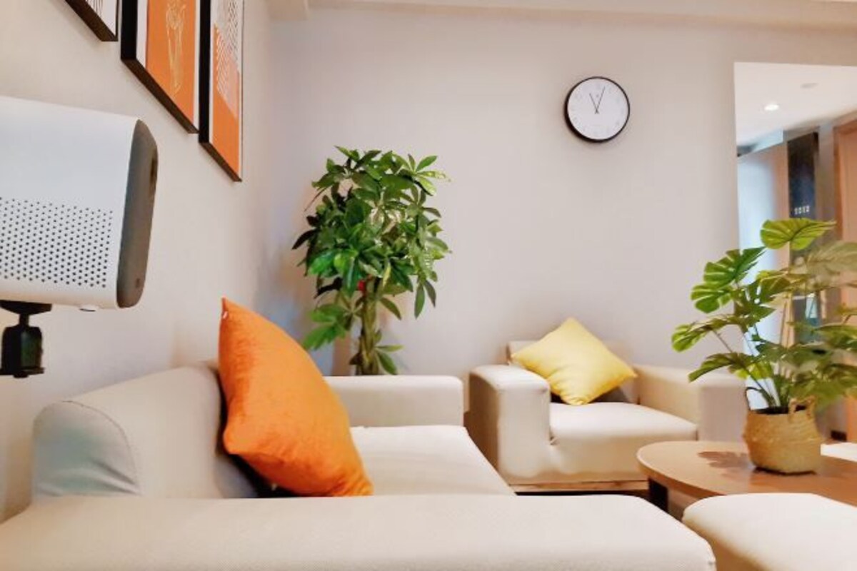 Una sala de estar moderna con un sofá, sillones, una mesita de centro y un reloj en la pared.