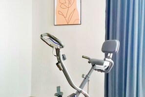An exercise bike in a room with a plain wall and a blue curtain. - Jinjiang Inn Select (Yangzhong Middle Yangzi Road) (Yangzhong)