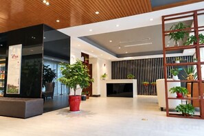 A modern lobby with a reception desk, seating area, and potted plants. - Jinjiang Inn Select (Yangzhong Middle Yangzi Road) (Yangzhong)
