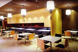 Un restaurante con varias mesas y sillas, iluminación colgante y una zona de mostrador.