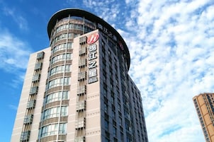 Un edificio de gran altura con una esquina curva, que presenta un letrero llamativo con caracteres chinos.
