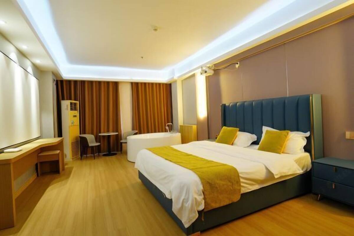 A hotel room with a bed, bedside table, desk, chair, and a small table.