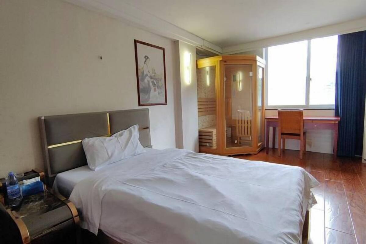 A hotel room with a bed, a desk, a chair, a wardrobe, and a window.