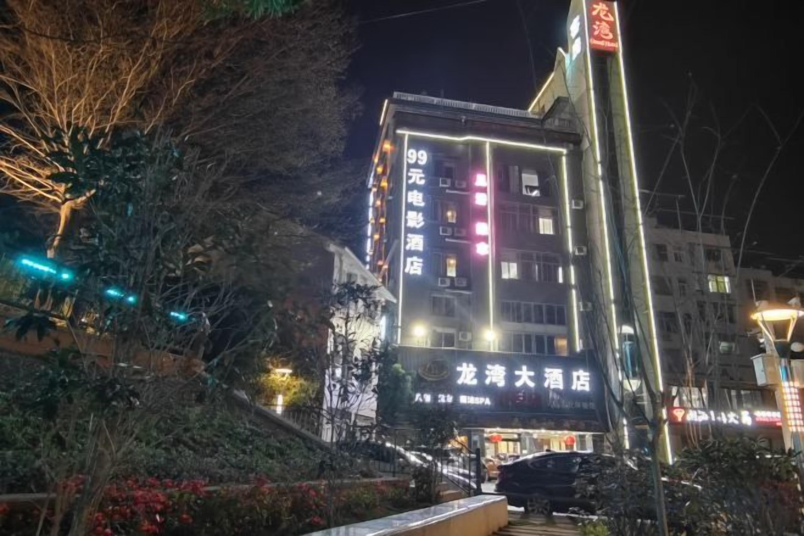 A multi-story building with illuminated signage, a visible entrance, and a staircase leading to the ground level.