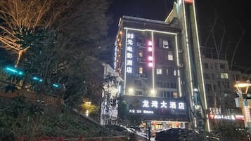 A multi-story building with illuminated signage, a visible entrance, and a staircase leading to the ground level.