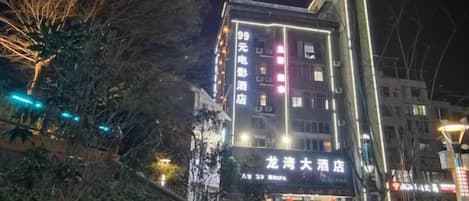 Un immeuble à plusieurs étages, doté d’une enseigne lumineuse, d’une entrée bien visible et d’un escalier menant au rez-de-chaussée.