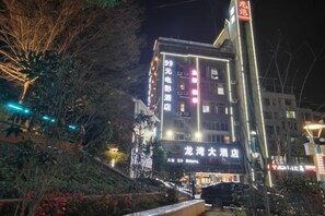 A multi-story building with illuminated signage, a visible entrance, and a staircase leading to the ground level. - Weishidun Hotel (Minqing)
