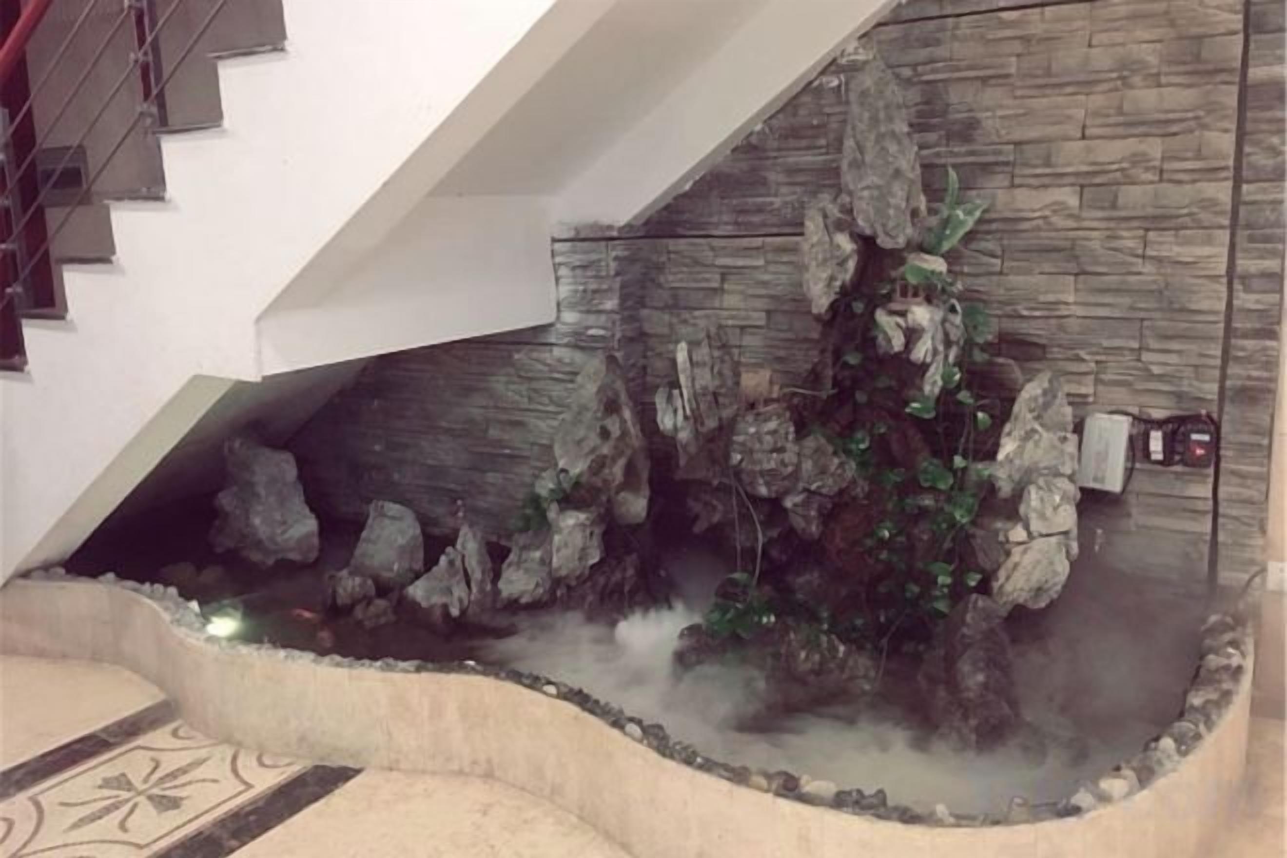 A stone wall with a water feature, a staircase, and a tiled floor.