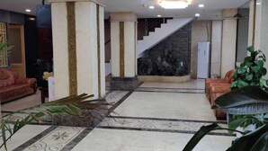 A lobby with a staircase, two sofas, a coffee table, and a refrigerator. - Weishidun Hotel (Minqing)