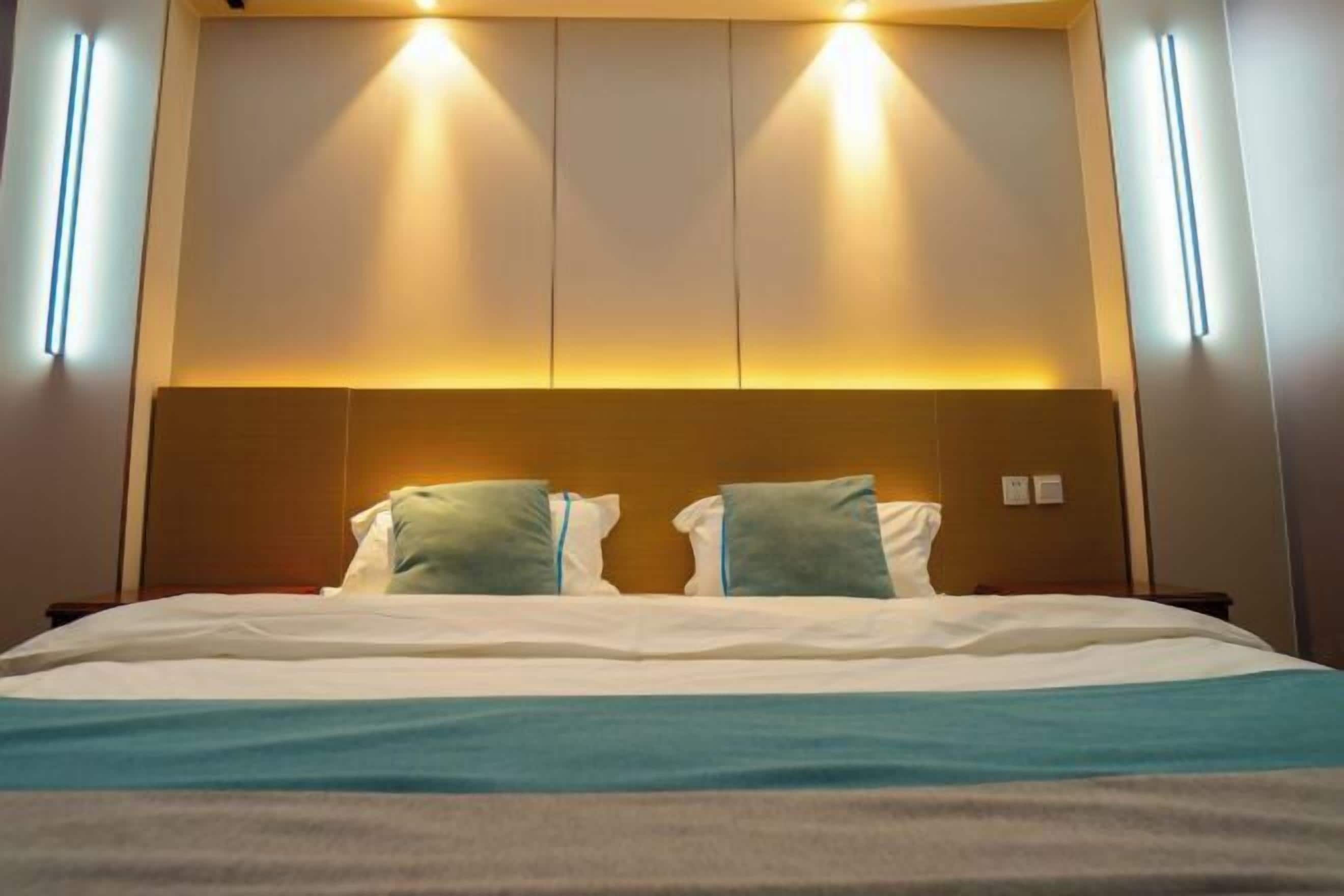 A hotel room with a bed, headboard, and bedside lamps.