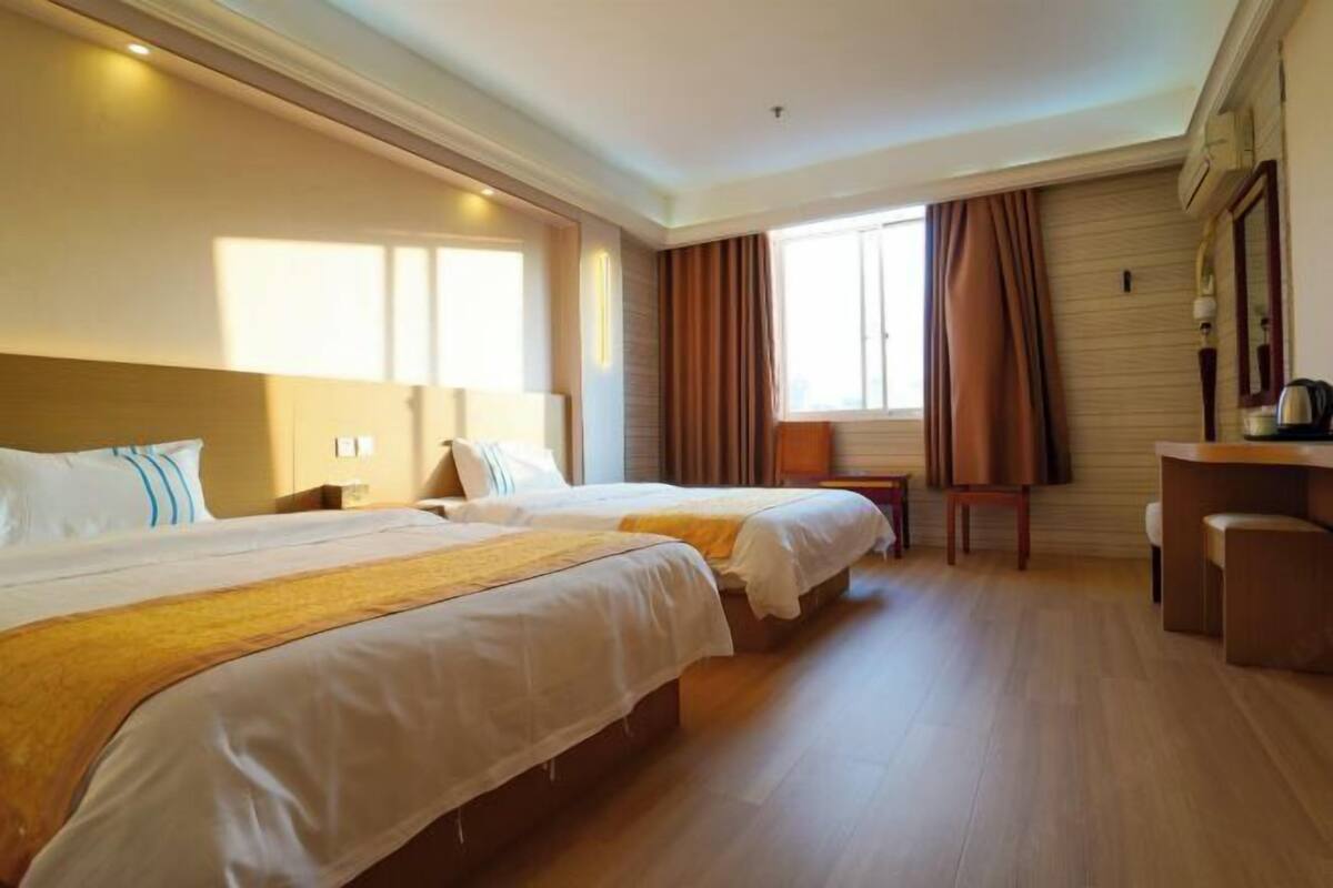 A hotel room with two beds, a desk, a chair, and a window with curtains.