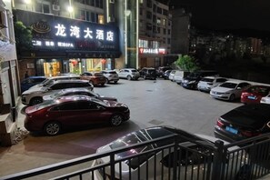 Un estacionamiento de hotel con varios coches aparcados, una entrada visible y un cartel.