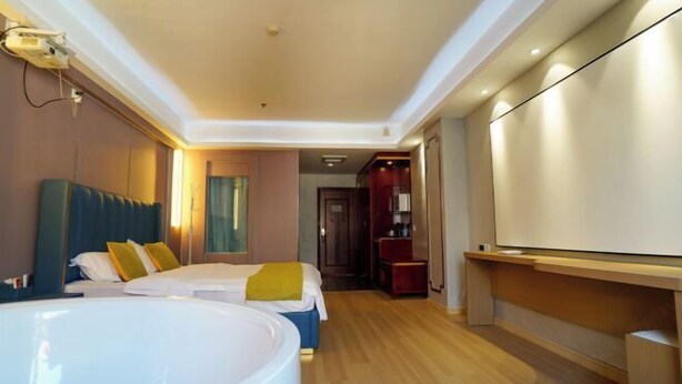 A hotel room with a large bed, a smaller bed, a desk, and a large bathtub. - Weishidun Hotel (Minqing)
