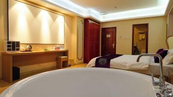 A hotel room with a large bed, a desk with a chair, a vanity with a mirror, and a bathtub.