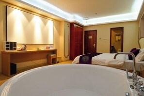 Habitación de hotel con una cama grande, un escritorio con silla, un tocador con espejo y una bañera.