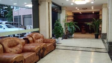 A lobby with a leather sofa, potted plants, and a reception desk.