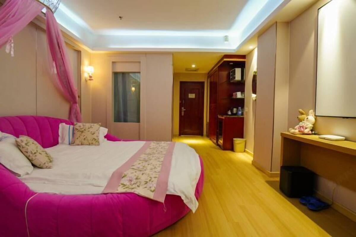 A bedroom with a large bed, a wardrobe, a vanity, and a hallway.