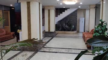 Un vestíbulo de hotel con una escalera, zona de estar y una pared decorativa.