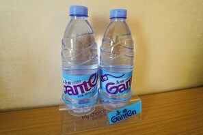 Dos botellas de agua transparentes de plástico, con tapas y etiquetas azules, sobre una superficie de madera con la etiqueta que dice 'My choice' y 'Ganten'.