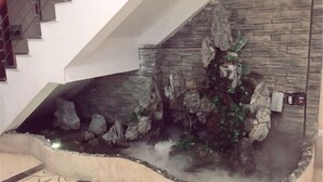A modern interior with a stone wall and a small indoor waterfall feature. - Weishidun Hotel (Minqing)