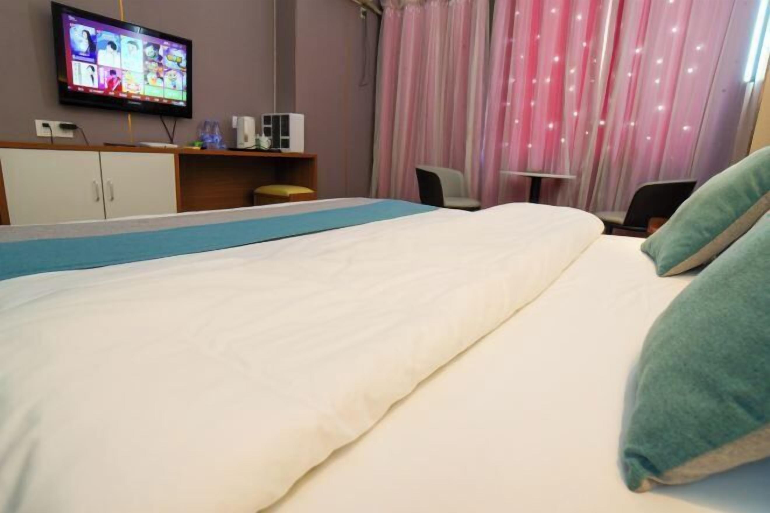 A hotel room with a bed, a television, a desk, and a chair.