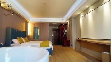A hotel room with a large bathtub, two beds, a TV, and a wooden floor.