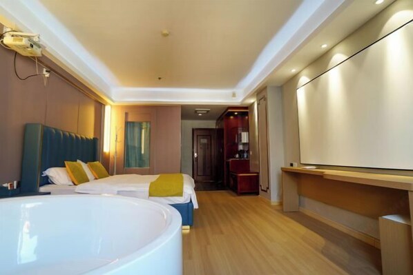 Habitación de hotel con una bañera grande, dos camas, un televisor y piso de madera.