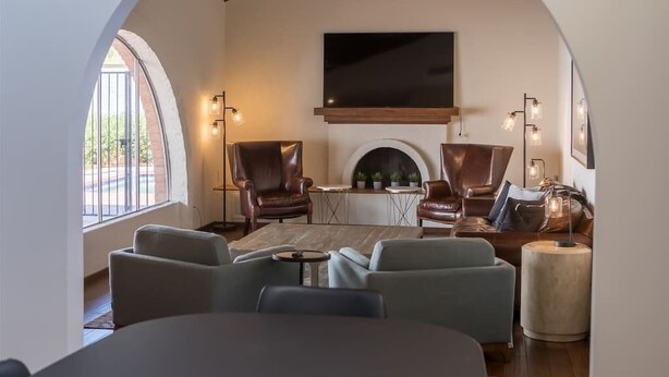 A cozy living room with leather sofas, a fireplace, and a large TV. - Spacious Arcadia Lite house w/ pool, mtn. views (Phoenix)