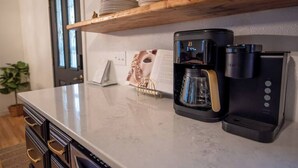 A kitchen with a coffee maker, a kettle, and a coffee machine on the counter. - Urban Edge | Comfort & Fun: Large Game Room & Fitness Room (Decorah)