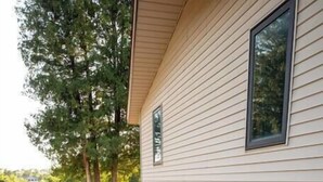 A house with a stone pathway leading to the entrance, surrounded by a landscaped garden with rocks and plants. - Urban Edge | Comfort & Fun: Large Game Room & Fitness Room (Decorah)