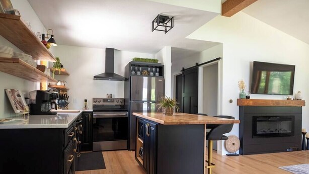 A modern kitchen with black cabinetry, a wooden island, and a built-in stove. - Urban Edge | Comfort & Fun: Large Game Room & Fitness Room (Decorah)