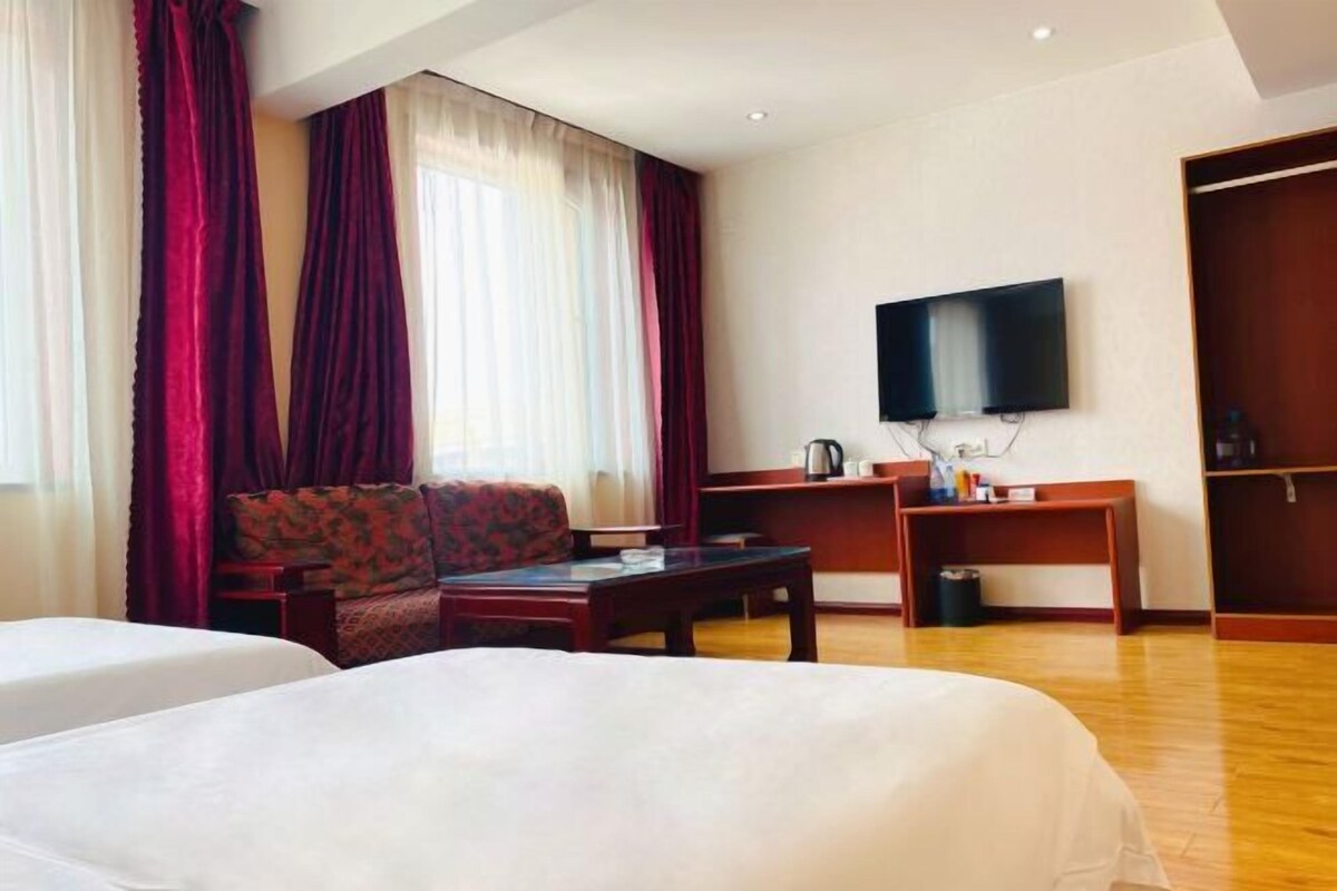 A hotel room with two beds, a TV, a desk, and a wardrobe.