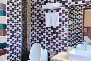 A bathroom with a tiled mosaic wall, a toilet, a sink, and a towel rack. - Yaqi Hotel (Pingdu)