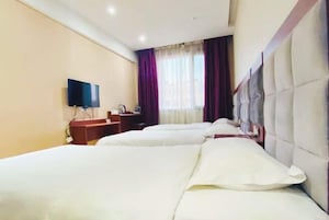 Habitación de hotel con dos camas, televisor, escritorio y ventana con cortinas.