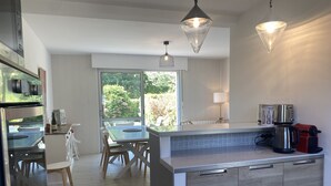 Una cocina moderna con comedor, ventanas amplias y una cafetera.