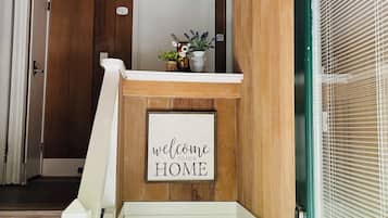 Et træinteriør med et skilt der siger 'welcome to our home', en trappe, en sofa og en lampe.
