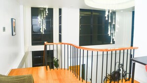 Ein modernes Interieur mit einer Holztreppe, schwarzer Geländer und einer Deckenleuchte.