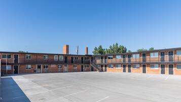 A multi-story brick building with a central staircase, a parking lot, and a clear blue sky.