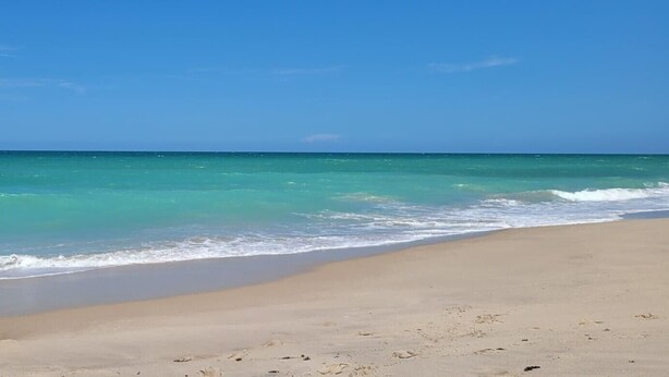 Een strand met helder turquoise water en een zandstrand.