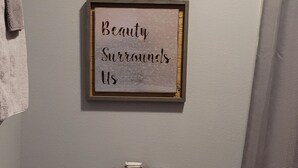 A bathroom with a toilet, a towel, and a framed sign on the wall. - #15 Off the Hook-Uncertain Lodge and Inn (Karnack)