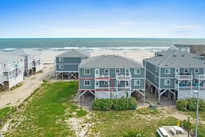A beachfront hotel with multiple buildings, a sandy beach, and the ocean in the background.