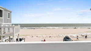Strandblick mit einem Gebäude, Badegästen und Fahrzeugen.
