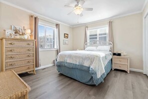 A bedroom with a bed, dresser, nightstand, and a ceiling fan. - Beach D-ehs by Brunswick Vacation Rentals: Oceanfront Condo with Pool on OIB (Ocean Isle Beach)