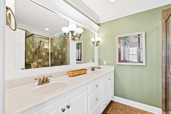 A bathroom with a large mirror, a white vanity, a glass shower enclosure, and a framed picture on the wall. - Rainbow's End by Brunswick Vacation Rentals: 6BR Oceanfront w/ Pool & Elevator (Supply)