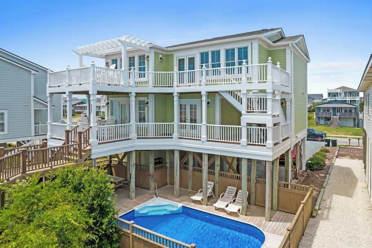 Une maison à plusieurs étages dotée d’une piscine, de balcons et d’une terrasse couverte.