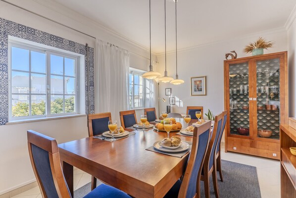 A dining area with a wooden table, chairs, and a glass cabinet with decorative items.
