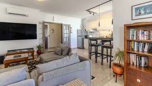 En moderne stue med en grå sofa, et fladskærms-tv, et sofabord og en reol.