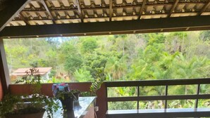 Une terrasse en bois avec une rambarde, des plantes en pot et deux tabourets.
